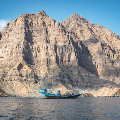Traditionelles Dhau-Boot vor der mächtigen Felswand des Shams